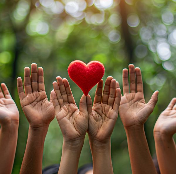 Many raised hands around a small red heart